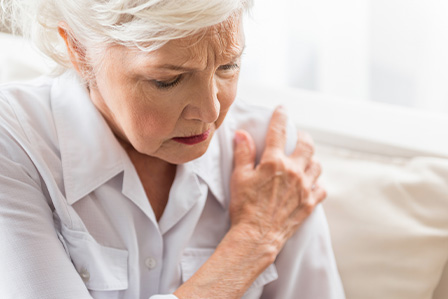 Older woman touches her shoulder in discomfort